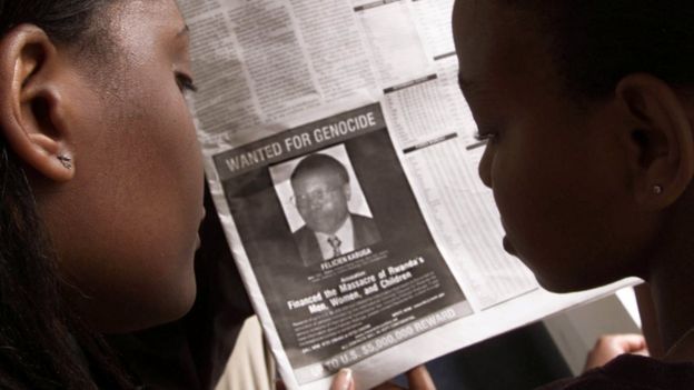 Readers look at a newspaper June 12, 2002 in Nairobi carrying the photograph of Rwandan Felicien Kabuga wanted by the United States