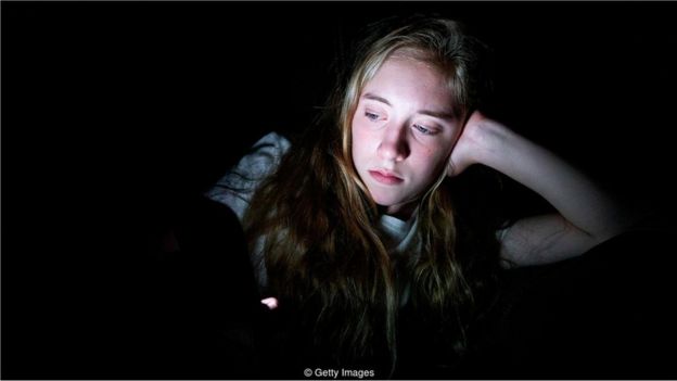 Menina no escuro com smartphone