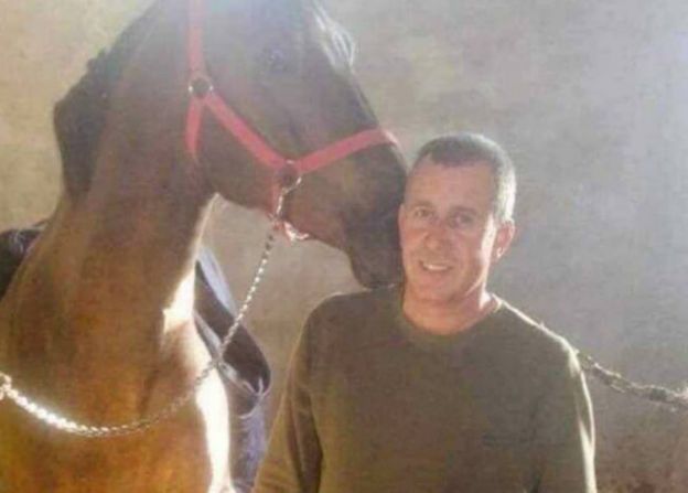 Khaled Mustafa smiling and standing with a horse