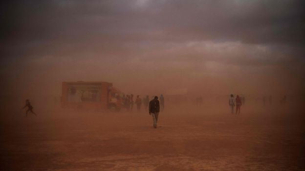 People walking to the mass in the dust