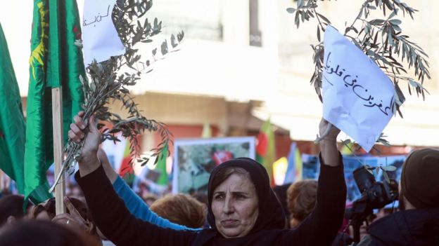 Syrian Kurdish woman holds up olive branches at a protest