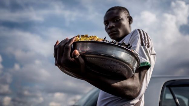 A street vendor carries a tray of his merchandise at a busy intersection in Yaounde, on October 1, 2018.