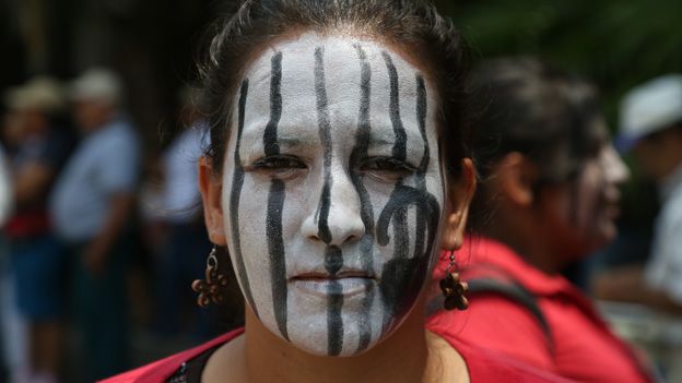 A woman with bars painted on her face takes part in a protest in El Salvador to demand a change in the country's abortion laws
