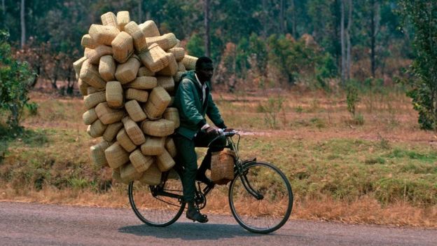 Un hombre en bicicleta en Uganda, cargado de paquetes.