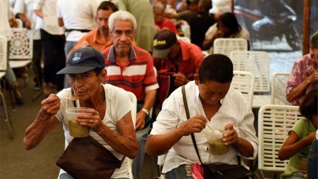People have some soup distributed during the campaign rally of Venezuelan opposition presidential candidate and evangelical pastor Javier Bertucci, in Catia, a Caracas neighbourhood, on May 12, 2018.