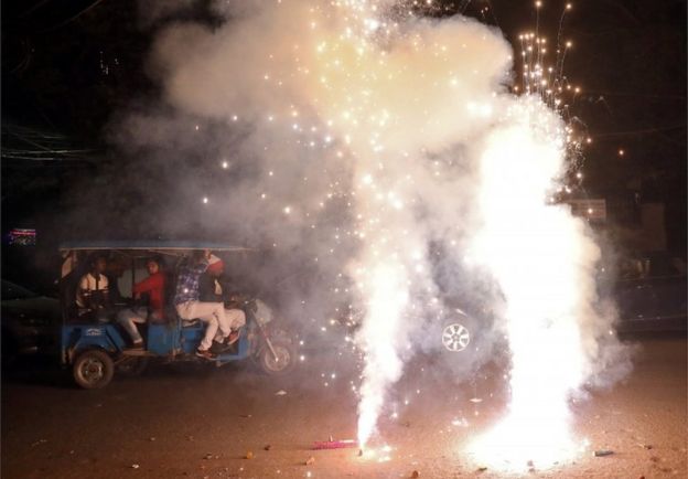 Men travel in a trishaw as firecrackers burn on a street during Diwali, the Hindu festival of lights, in New Delhi, India, November 7, 2018