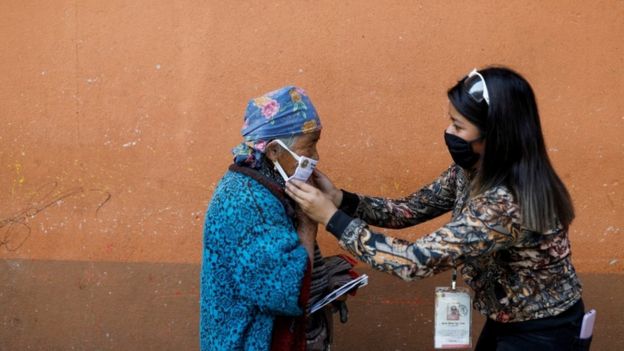 A municipal worker adjusts a protective face mask on a woman on the street amid the outbreak of the coronavirus disease (COVID-19), in Totonicapan, Guatemala April 19, 2020