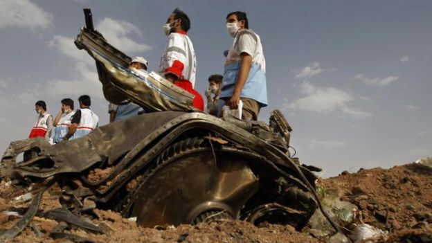 Members of Iran's Red Crescent stand near a piece of the Caspian Airlines Tupolev-154, which crashed near the city of Qazvin, north-west of Tehran (16 July 2009)