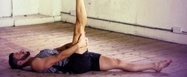man lying down with one leg up stretching his hamstring