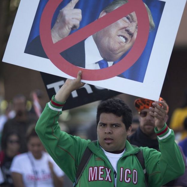 Joven mexicano sostiene un cartel anti Trump