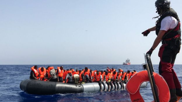 A crew member of the "Ocean Viking" rescue ship helps migrants in a dinghy on 9 August