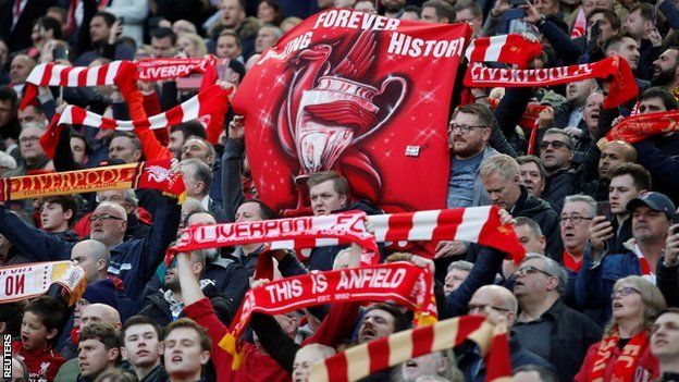 Celebrating Liverpool fans holding up scarves and banners