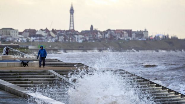 A man walks a dog along the promenade near Blackpool as gusts of up to 80mph could hit parts of the UK as Storm Brendan sweeps in.