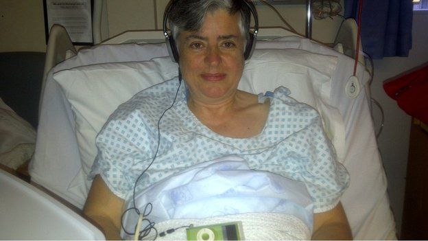 Researcher in hospital bed listening to music on headphones after surgery