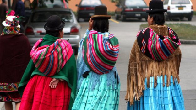 Peruanas caminando en la ciudad con faldas y ponchos de la sierra.