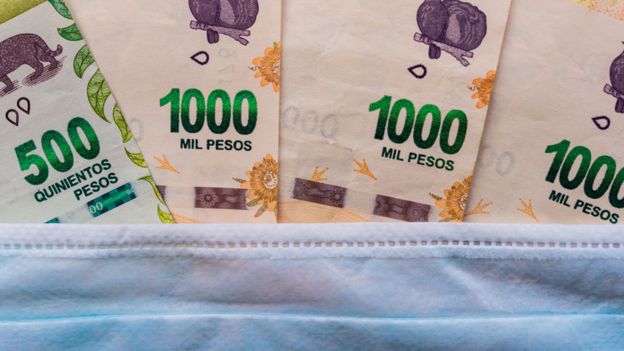 Billetes de pesos debajo de una mascarilla