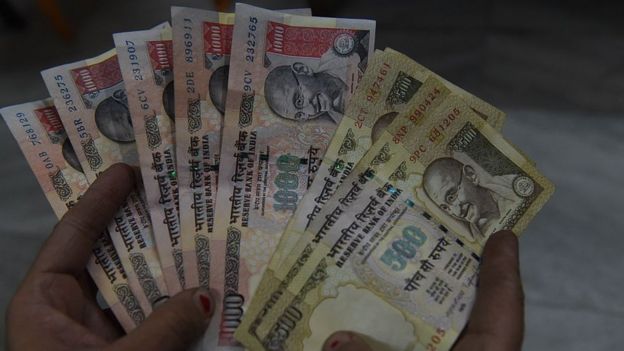 An Indian resident holds 500 and 1000 rupee notes.