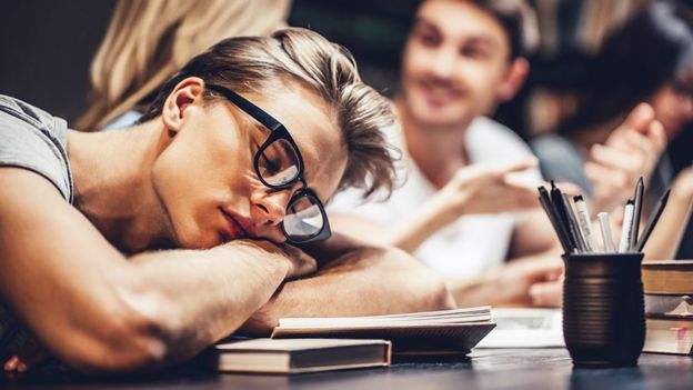 Una estudiante durmiendo sobre sus libros.