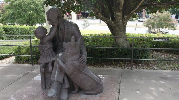 A statue of a man and his guide dog interacting with a little girl outside the Texas School for the Blind and Visually Impaired