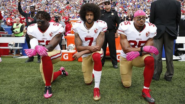 Eli Harold, Colin Kaepernick and Eric Reid kneeling during the national anthem