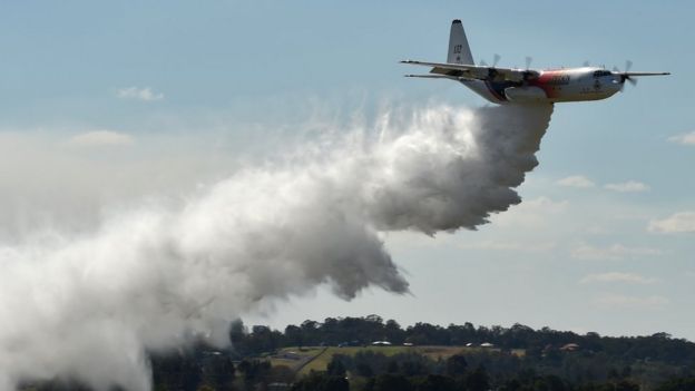 A NSW Rural Fire Services Hercules C-130 large air tanker drops water in an exercise over western Sydney in 2017