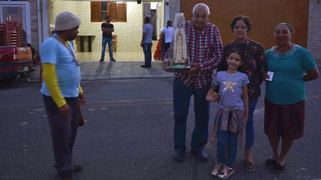 Brasilina de Medeiros Gonçalves junto a su nieta de 7 años y otros fieles. Uno de ellos sostiene una imagen de la virgen
