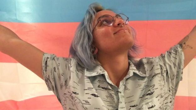 Julian segurando bandeira do orgulho transgênero