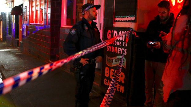 Apoliceman refuses to let members of the public walk on to a street that has been blocked after police arrested four people in raids across Sydney, July 29, 2017.