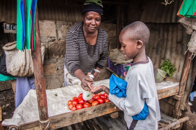 Hellen Mong'ina le da gel desinfectante a un niño en su puesto de Kibera, Kenia, el 1 de abril de 2020.