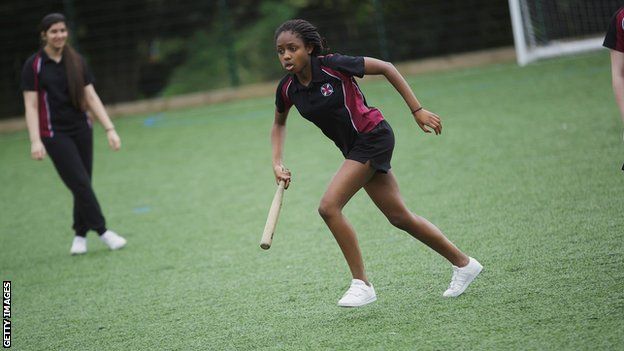 A young girl playing rounders in England
