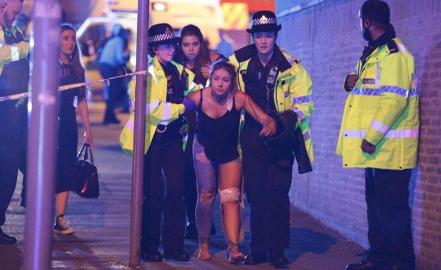 Mujer herida camina acompañada de varios agentes de policía