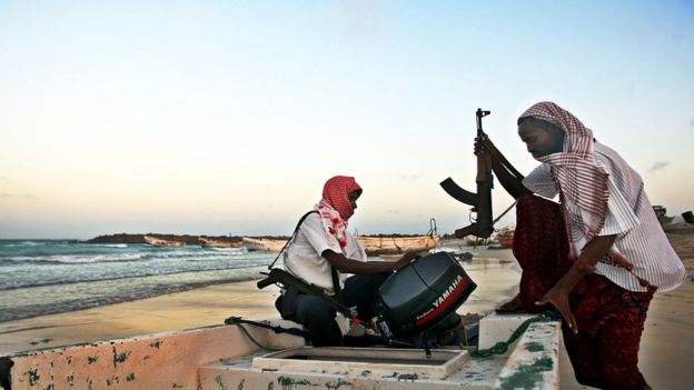 Somali men with guns getting aboard a small boat
