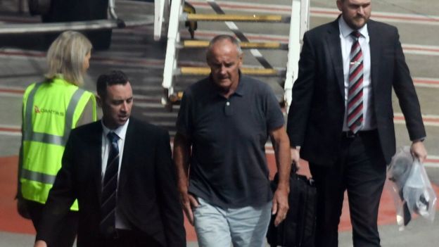 Chris Dawson is escorted off a flight by New South Wales Police detectives in Sydney