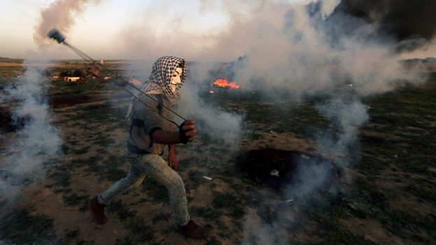 A Palestinian uses a sling to hurl a tear-gas canister during a protest on the Gaza-Israel border fence in the central Gaza Strip on 15 February 2019