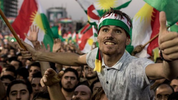 A supporter stands out form the throng, lifted on other's shoulders in a large crowd waving the Kurdish region's flag earlier this week