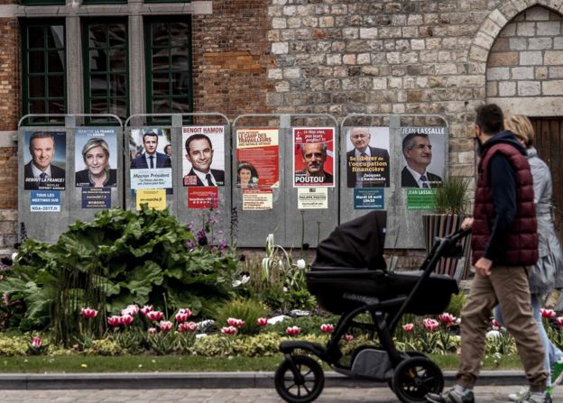 People walk past campaign posters of French presidential election candidates in Bailleul, northern France. 21 France