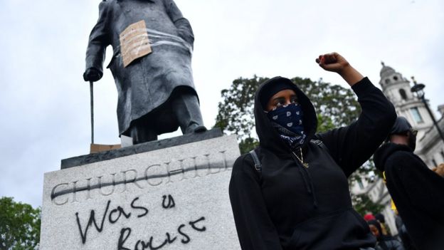 A protester stands in front of the Churchill statue