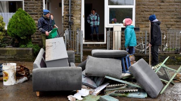 Residents stand outside with ruined furniture in West Yorkshire