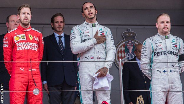 Lewis Hamilton stands on the podium