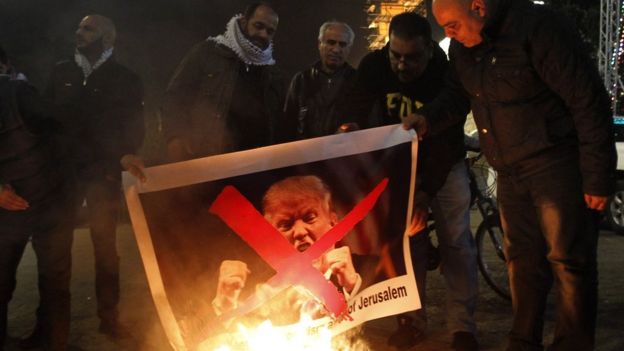 Palestinian protesters burn pictures of US President Donald Trump at the manger square in Bethlehem on December 5, 2017