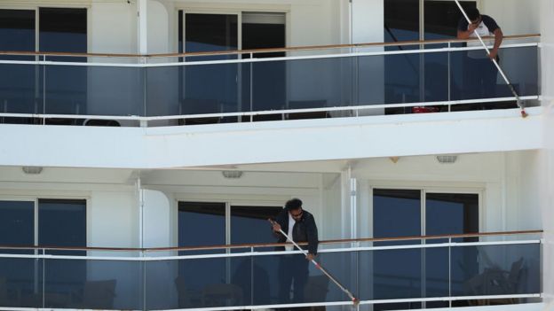 Dos hombres limpian los balcones del crucero.