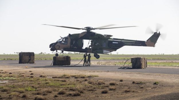 Australian defence staff load a helicopter with hay bales in northern Queensland's cattle region