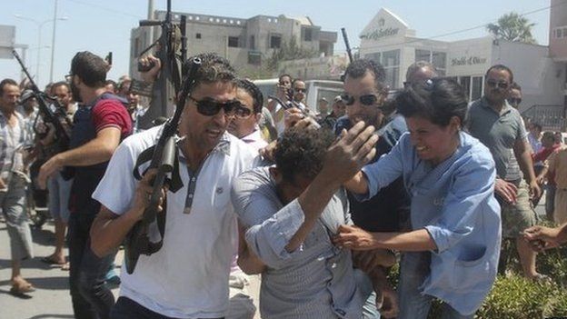 Police officers control the crowd while surrounding a man suspected to be involved in opening fire on a beachside hotel in Sousse