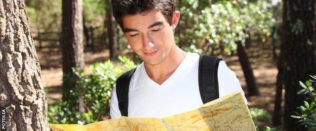 young man looking at a map while on a hike