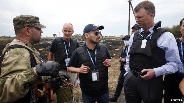 Organization for Security and Co-operation in Europe (OSCE) monitors speak with a pro-Russian separatist (left) at the crash site of Malaysia Airlines Flight MH17, near the settlement of Grabove in the Donetsk region, Ukraine, 19 July 2014