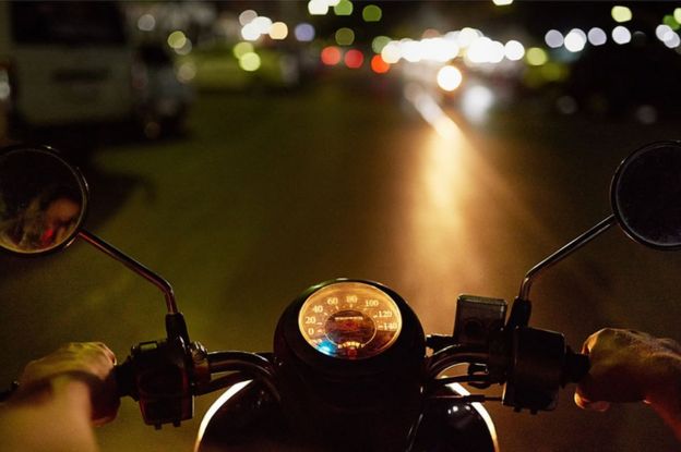 Motociclista circulando en la noche.