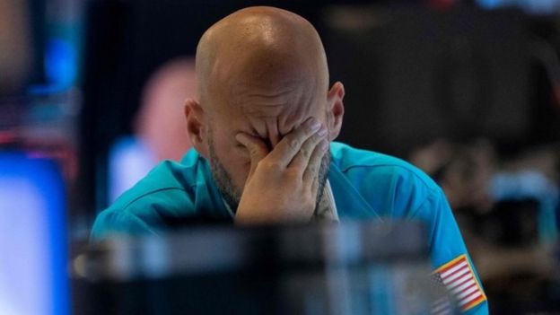 Un comerciante se limpia los ojos mientras mira los precios de las acciones en la Bolsa de Nueva York el 23 de agosto