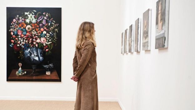 سيدة تقف في صالة لعرض الأعمال الفنية