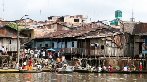 Gente en botes frente a casas en el Amazonas