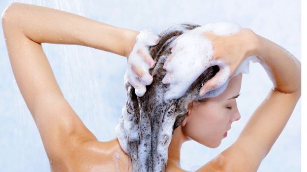 Una mujer se lava el pelo en la ducha